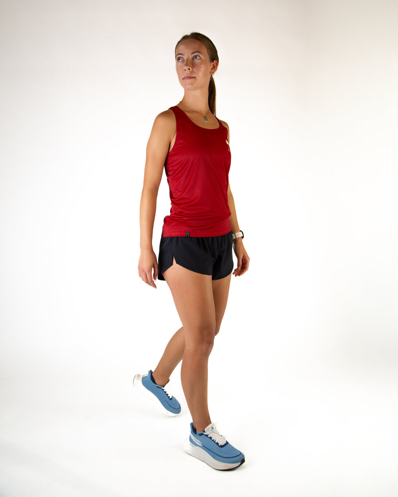 Runner is wearing ChicknLegs in the women's performance running singlet in the cardinal red solid color.