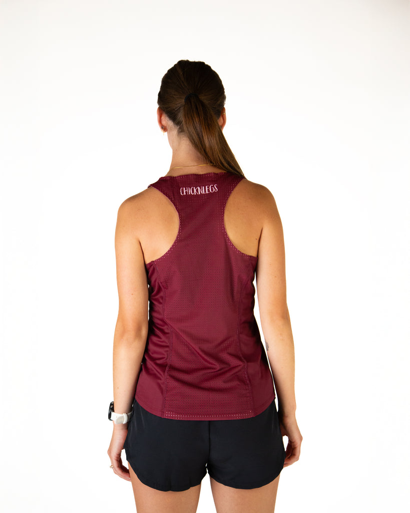 Runner is wearing ChicknLegs in the women's performance running singlet in the maroon solid color. Breathable mesh back is shown of the singlet.
