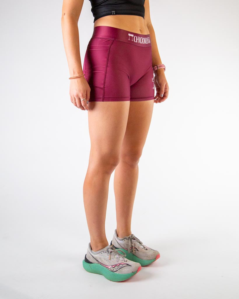 Right side view of ChicknLegs women’s 3-inch compression shorts in solid maroon pattern, high-rise waistband, and functional side pocket.