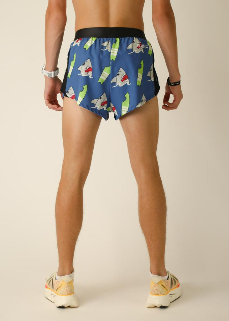 Model wearing Chicknlegs men's 2 inch split running shorts in the blue sharks design, facing the back for back view of shorts.