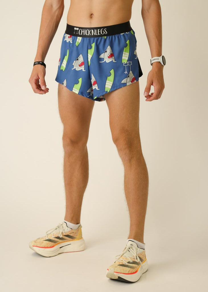 Model wearing Chicknlegs men's 2 inch split running shorts in the blue sharks design, facing left for left side view.