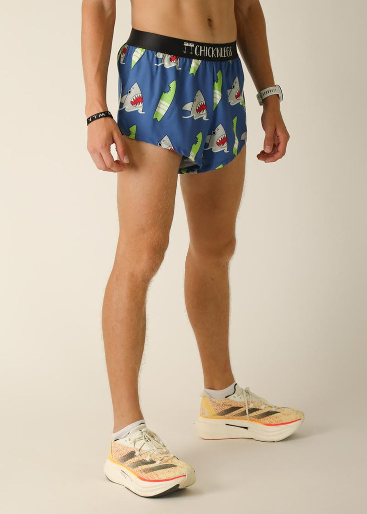 Model wearing Chicknlegs men's 2 inch split running shorts in the blue sharks design, facing right for right side view.