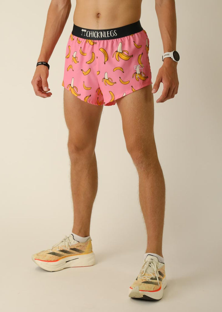 Model wearing Chicknlegs men's 2 inch split running shorts in the pink bananas design, facing left for left side view.