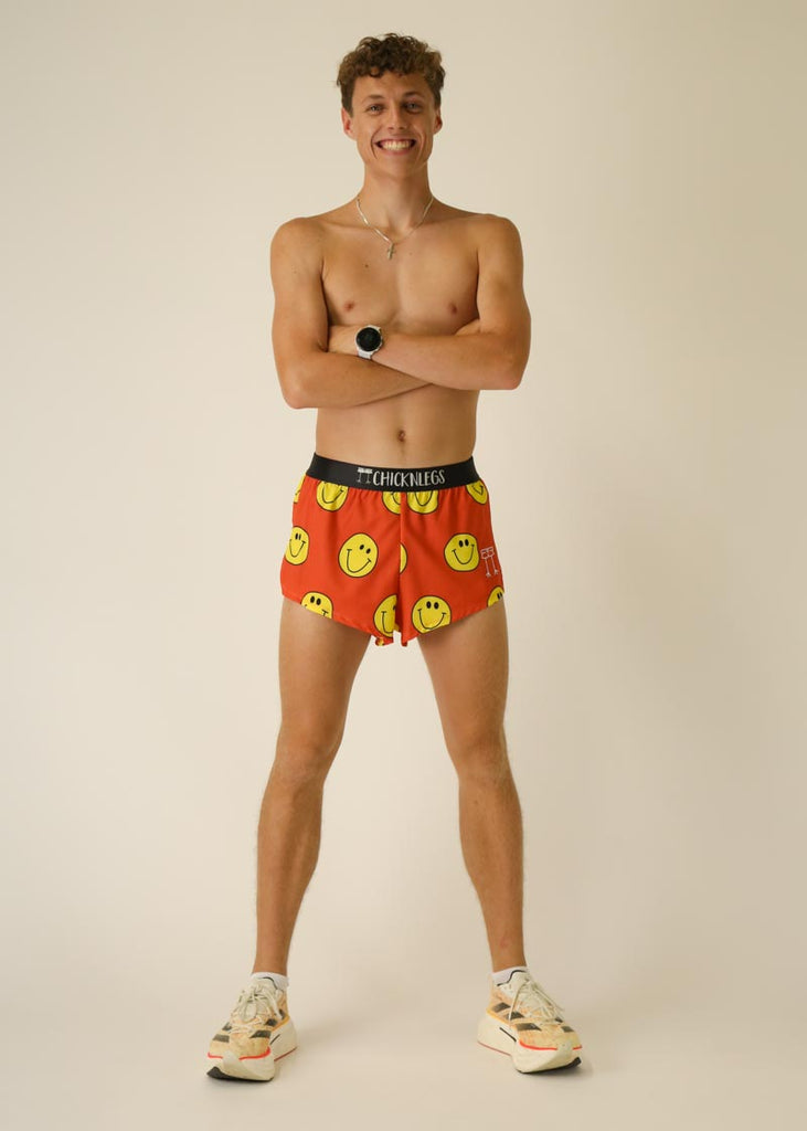 Model wearing Chicknlegs men's 2 inch split running shorts in the smiley design, crossing arms and posing with a smile.