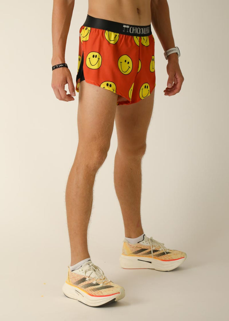 Model wearing Chicknlegs men's 2 inch split running shorts in the smiley, facing right for right side view.