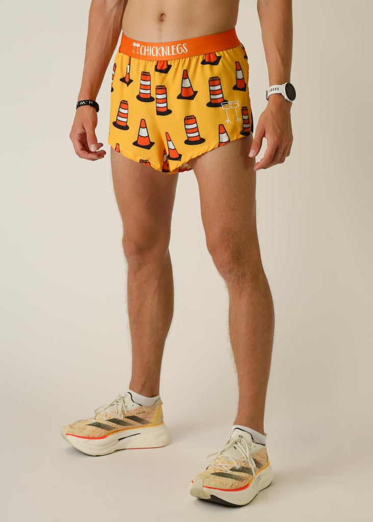 Model wearing Chicknlegs men's 2 inch split running shorts in the traffic cones design, facing left on left side view.