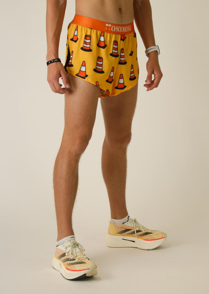 Model wearing Chicknlegs men's 2 inch split running shorts in the traffic cones design, facing right on right side view.