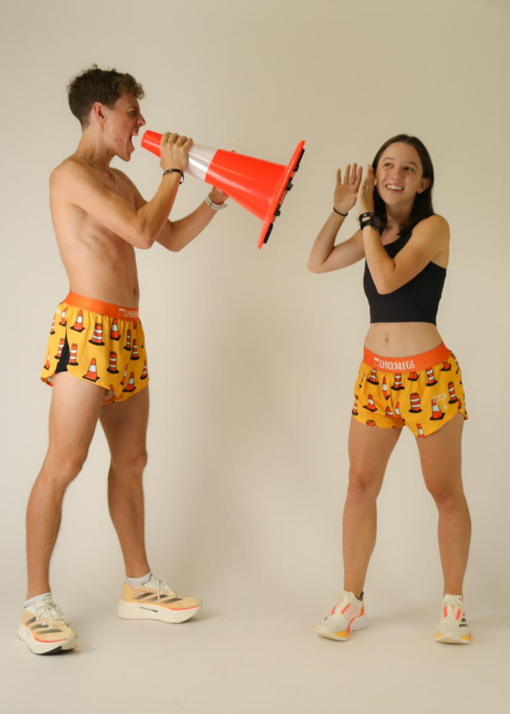 Model wearing Chicknlegs men's 2 inch split running shorts in the traffic cones design in a group photo.