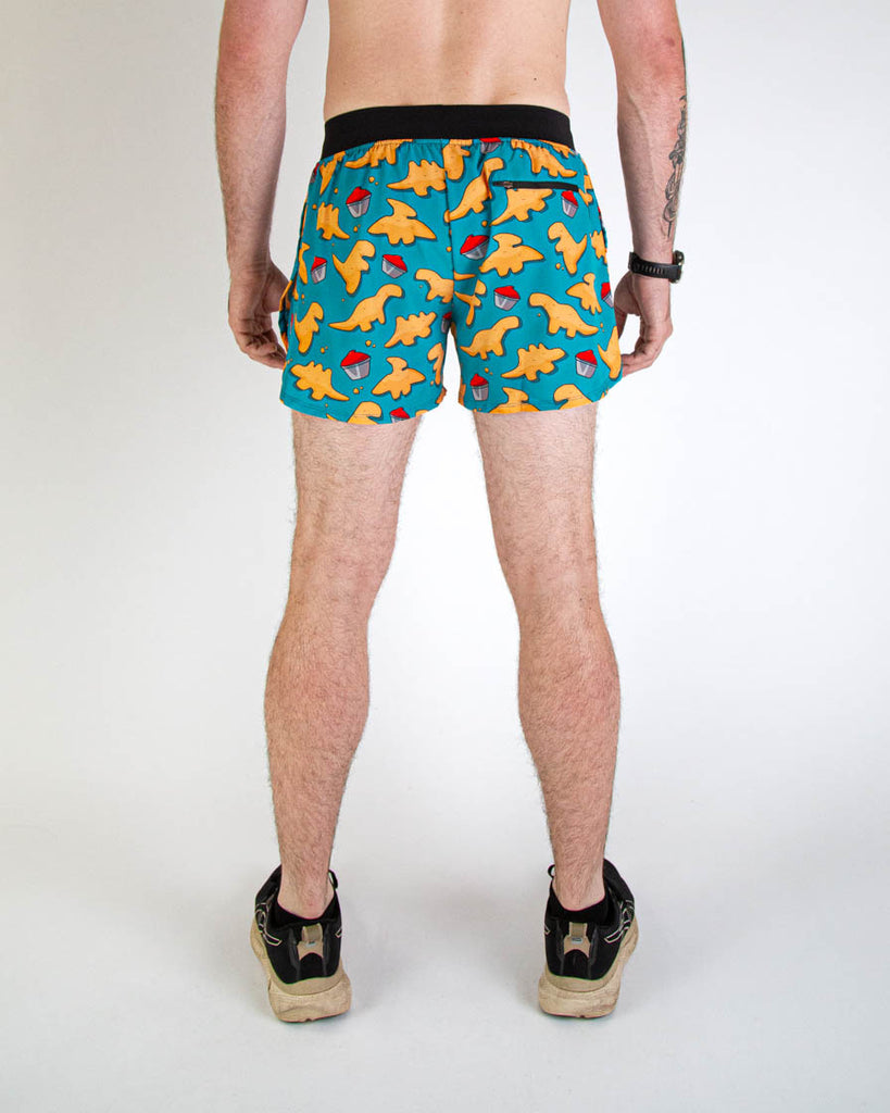 Back view of ChicknLegs men's 4-inch split running shorts with breathable liner, blue background and brown and orange dino nuggets with ketchup all over, with a black waistband and back pocket. Paired with black runners shoes.