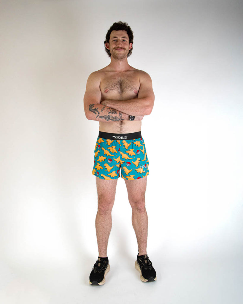 Full body view of ChicknLegs men's 4-inch split running shorts with breathable liner, blue background and brown and orange dino nuggets with ketchup all over, with a black waistband and back pocket.