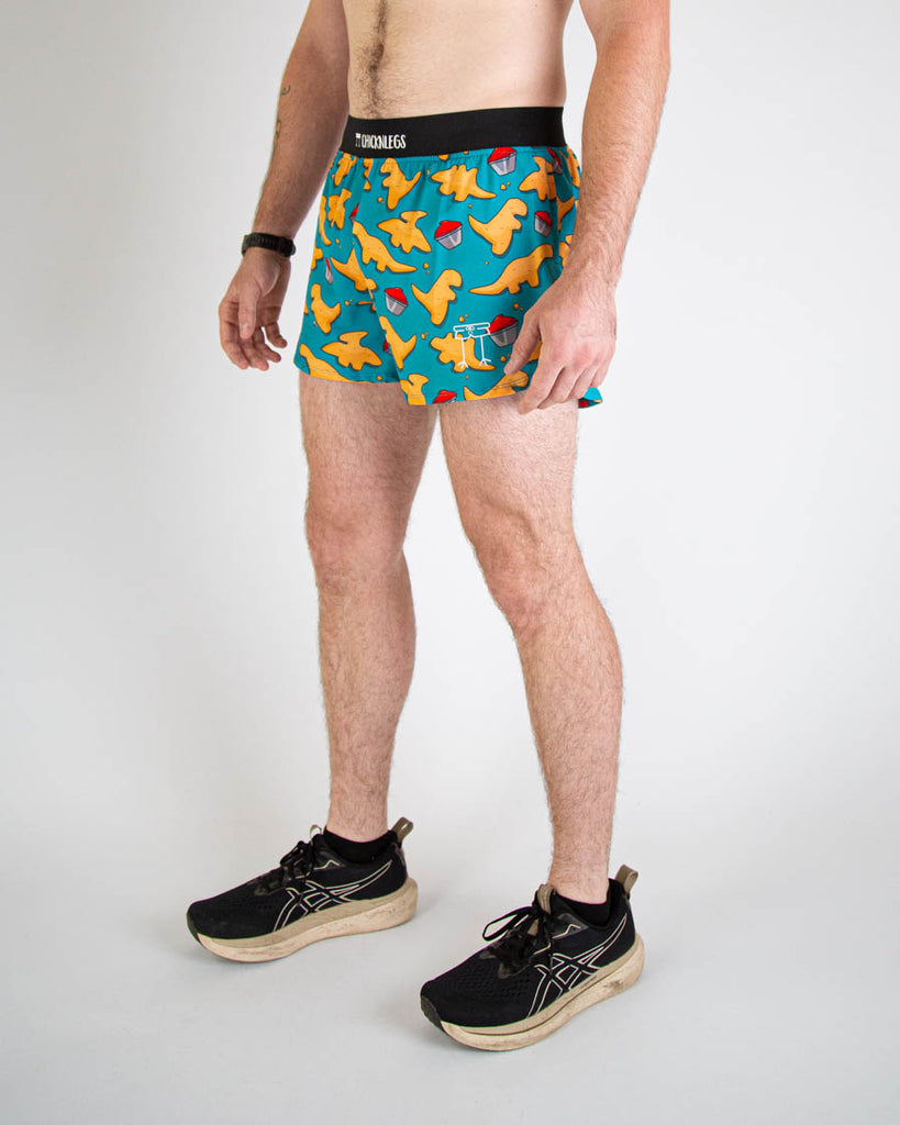 Left side view of ChicknLegs men's 4-inch split running shorts with breathable liner, blue background and brown and orange dino nuggets with ketchup all over, with a black waistband and back pocket.