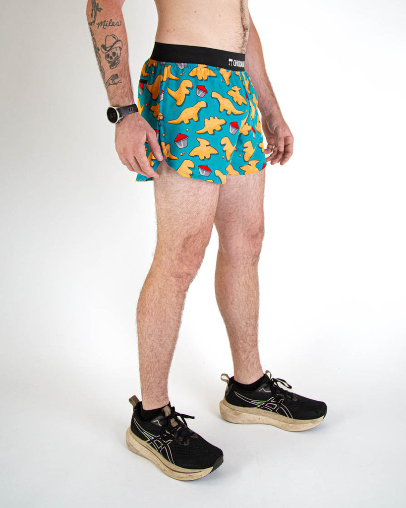 Front view of ChicknLegs men's 4-inch split running shorts with breathable liner, blue background and brown and orange dino nuggets with ketchup all over, with a black waistband and back pocket. Paired with black shoes.