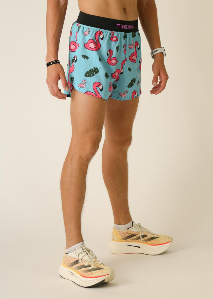 Model wearing Chicknlegs in men's 4 inch split running shorts in the blue flamingo design, facing right side view.