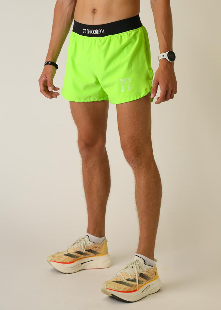 Model wearing Chicknlegs men's 4 inch split running shorts in the neon green design, facing left for left side view.