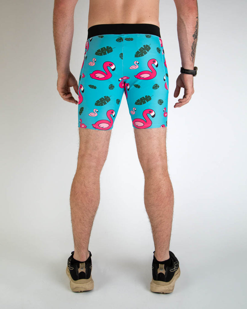 Back view of ChicknLegs men's 8-inch compression spandex running half tights with breathable liner, blue background and pink flamingos, with a black waistband and side pockets.