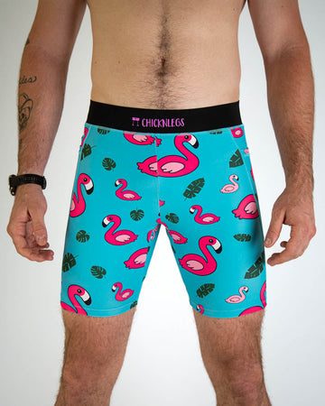 A close up view of ChicknLegs men's 8-inch compression spandex running half tights with breathable liner, blue background and pink flamingos, with a black waistband and side pockets.