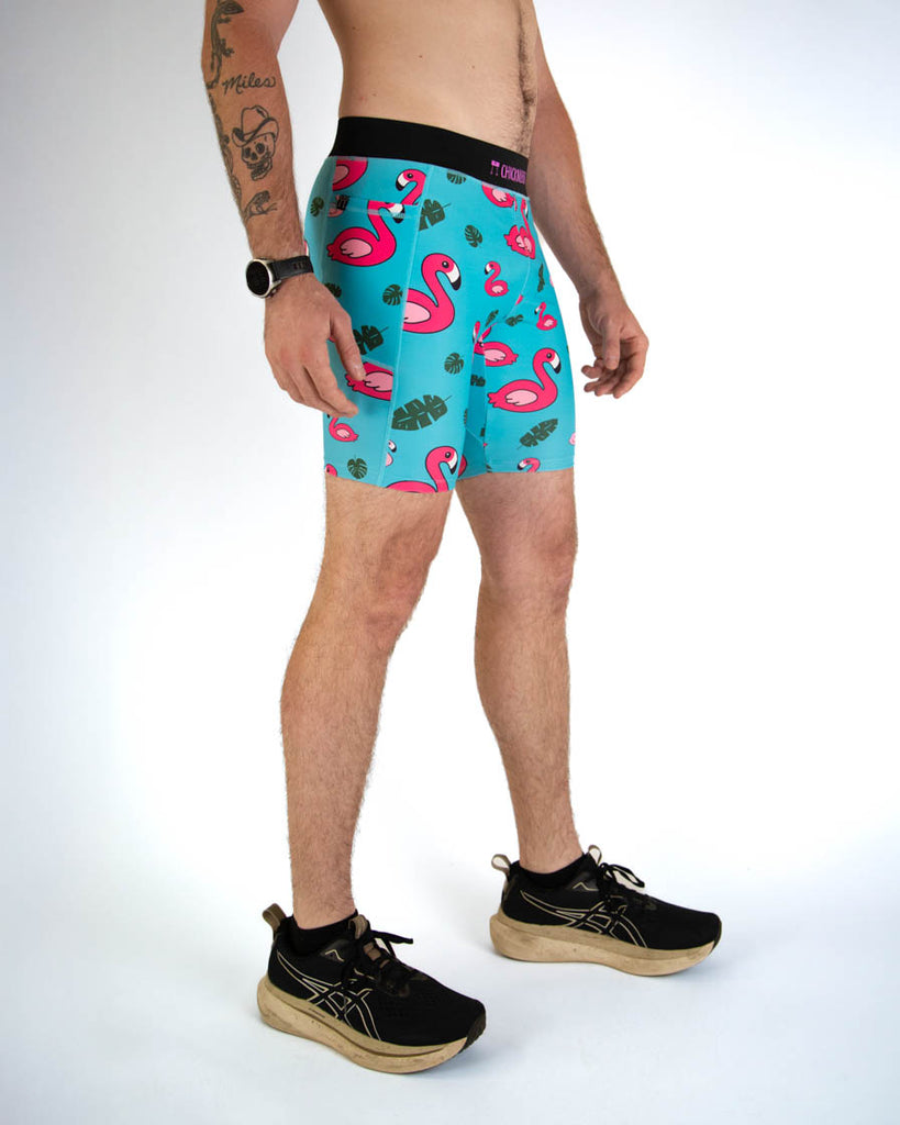 Right view of ChicknLegs men's 8-inch compression spandex running half tights with breathable liner, blue background and pink flamingos, with a black waistband and side pockets.