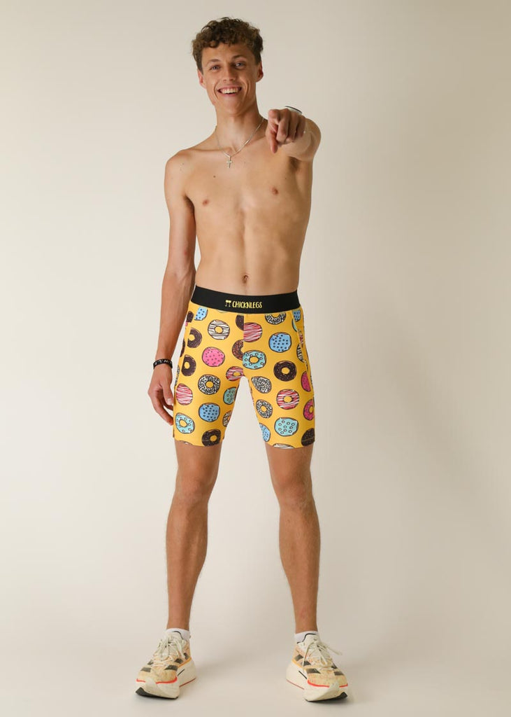 Model wearing Chicknlegs men's 8 inch half tights in the salty donuts design,  full body view posing while pointing.