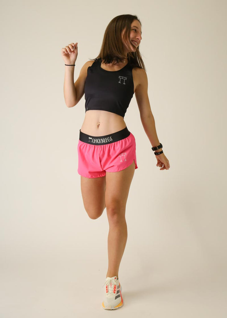 Model wearing Chicknlegs women's 1.5 inch split running shorts in the neon pink design posing cheerfully.