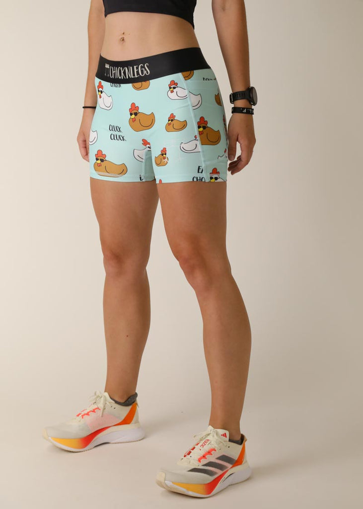 Model is wearing Chicknlegs women's 3 inch compression shorts for running in the swaggy chicken design, facing left for left side view.