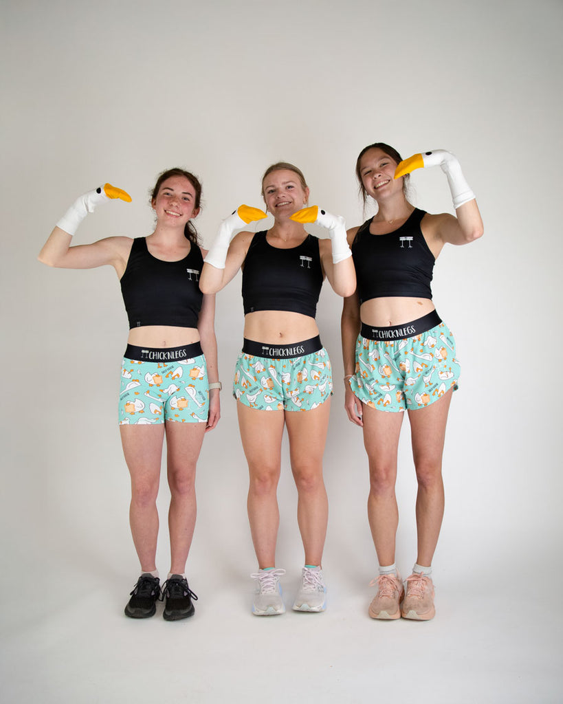Runner is wearing ChicknLegs in the women's 1.5 in split running shorts in the silly goose design. The print has orange, white and blue on it. 
