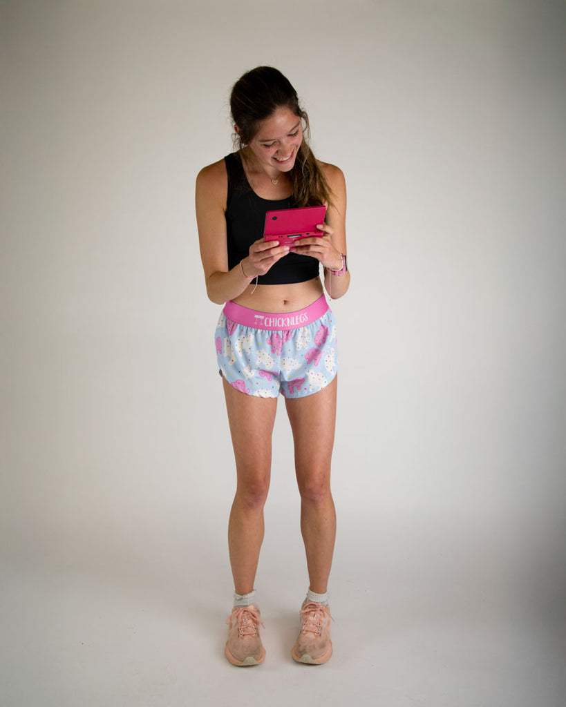 Runner is wearing ChicknLegs in the women's 1.5 in split running shorts in the animal cookies design. The print has white, pink and blue on it. A ton of fun frosted covered animal cookies with rainbow sprinkles. 