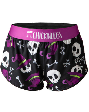 Ghost image is from ChicknLegs women's 1.5 in split running shorts in the skulls design. The print has skeleton skull, witch hats and bones. The print has purple, green, and black.