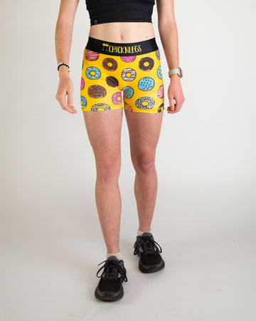 Runner is wearing ChicknLegs in the women's 3 in compression spandex shorts in the salty donuts design. Fun print with food in blue, brown, pink, yellow, red, orange, green, colors! Great for the track and field.