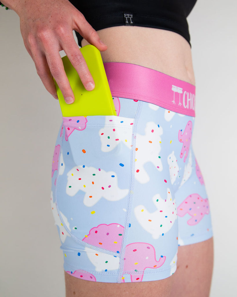 Close up image is shown of the women's 3 in compression spandex shorts of the animal cookies with the model putting the phone into the pocket.