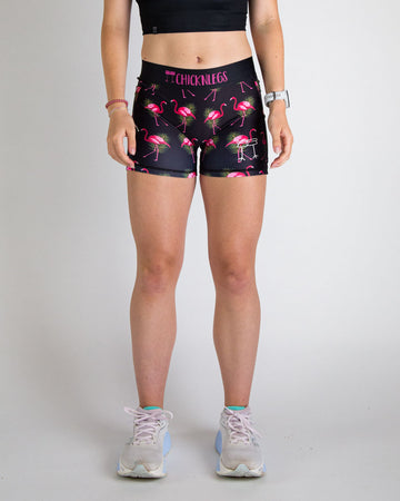 Runner is wearing ChicknLegs in the women's 3 in compression spandex shorts in the black flamingo design. The print has bright pink flamingos on it with green leaves on a black background.