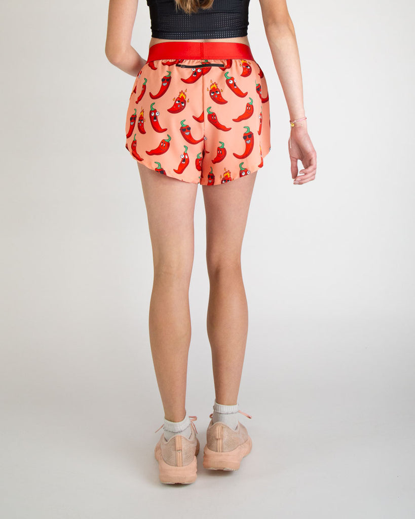 Runner is wearing ChicknLegs in the women's 4 in split running shorts in the chili pepper design. The print has fun red, green and orange all over it for people who love spicy. Back of the shorts have a zipper on it to store air pods, phones, snacks, and any other runners gear.