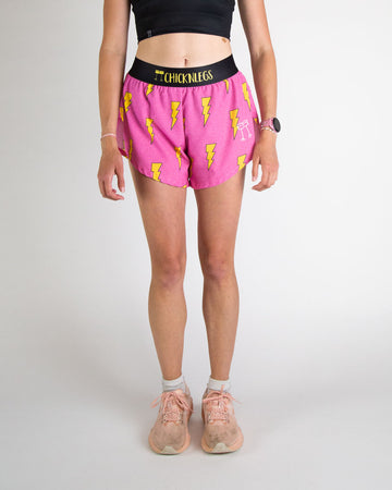 Runner is wearing ChicknLegs in the women's 4 in split running shorts in the hot pink bolts design. The print has a bright neon pink background with yellow electric lightning bolts.