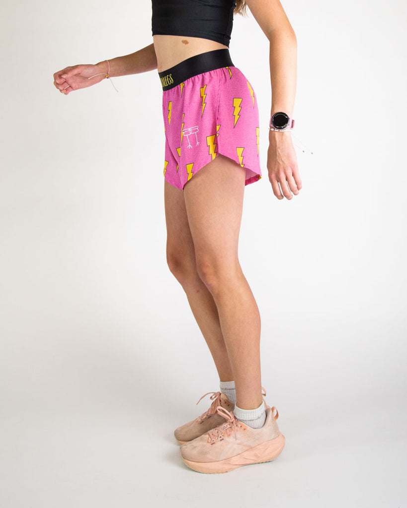 Runner is wearing ChicknLegs in the women's 4 in split running shorts in the hot pink bolts design. The print has a bright neon pink background with yellow electric lightning bolts. Great for long distance, hiking, running, track, field, working out and weight lifting.