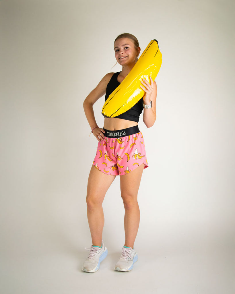 Runner is wearing ChicknLegs in the women's 4 in split running shorts in the pink banana shorts. The print has yellow and pink on it. 