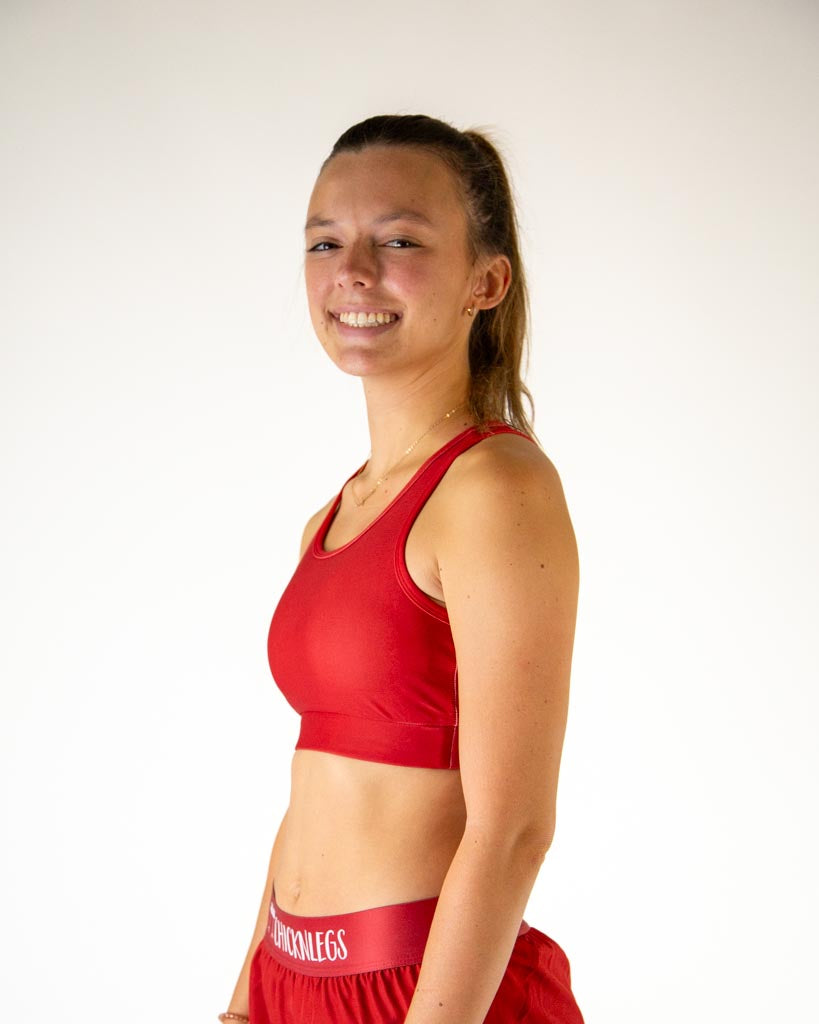 Left side view of ChicknLegs women’s og sports bra in solid cardinal red, showing racerback strap and supportive fit.