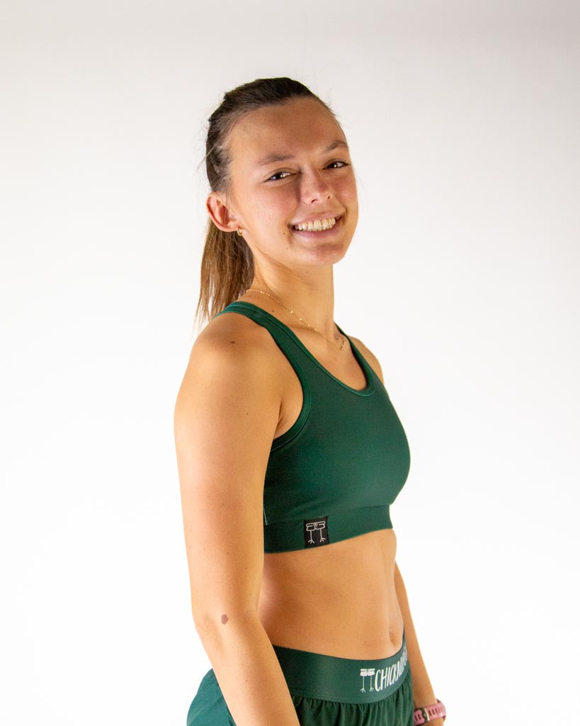 Right side view of ChicknLegs women’s OG sports bra in forest green color and elastic underband.