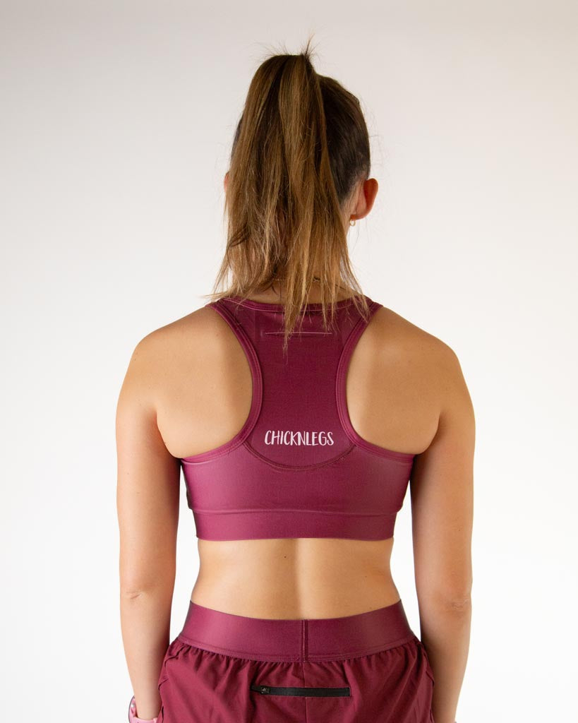Back view of ChicknLegs women’s og sports bra in solid maroon featuring racerback design and breathable stretch fabric with a phone pocket.