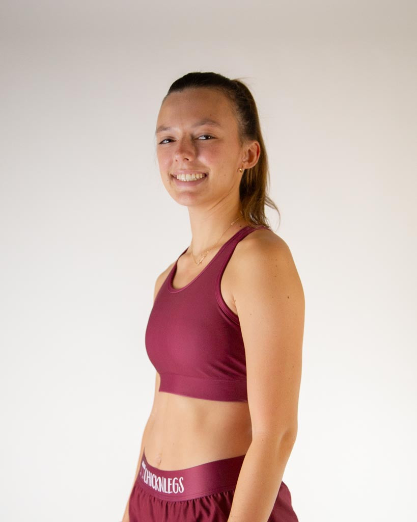 Left side view of ChicknLegs women’s OG sports bra in solid maroon, showing racerback strap and supportive fit.