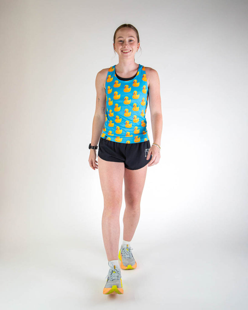 Full body view of model wearing ChicknLegs men’s 2-inch split running shorts in hot pink with yellow lightning bolts, styled with yellow running shoes.