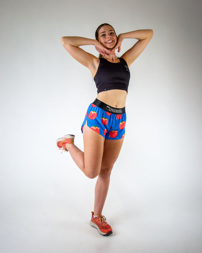 Full body view of ChicknLegs women’s 1.5-inch split running shorts with drawstring, breathable liner, blue background and juicy peaches design.