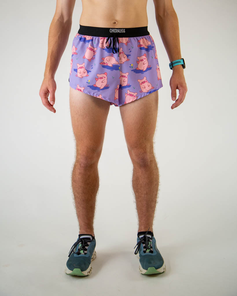Front view of ChicknLegs men’s 2-inch split running shorts with drawstring, breathable liner, lilac purple background and pink piggies design.
