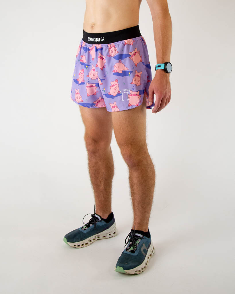 Left side view of ChicknLegs men’s 4-inch split running shorts, breathable liner, lilac purple background and pink piggies on the design with a black waistband.