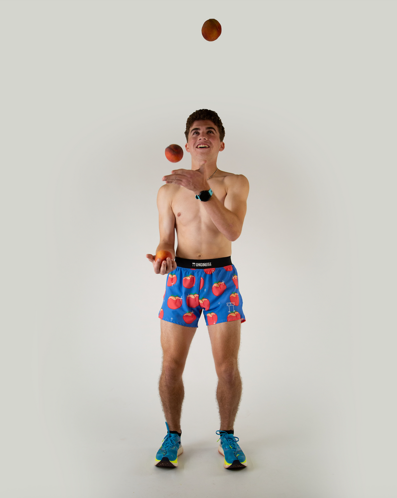 Full body view of ChicknLegs men’s 4-inch split running shorts with, breathable liner, blue background and juicy peaches on the design.