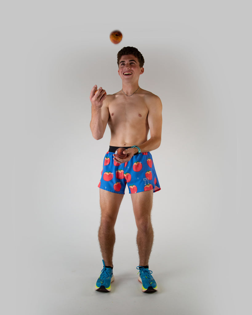 Full body view of ChicknLegs men’s 4-inch split running shorts with, breathable liner, blue background and juicy peaches on the design.