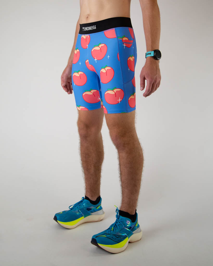 Left side view of ChicknLegs men’s 8-inch half tights, breathable liner, blue background and juicy peaches design. Side pockets are visible in the photo.