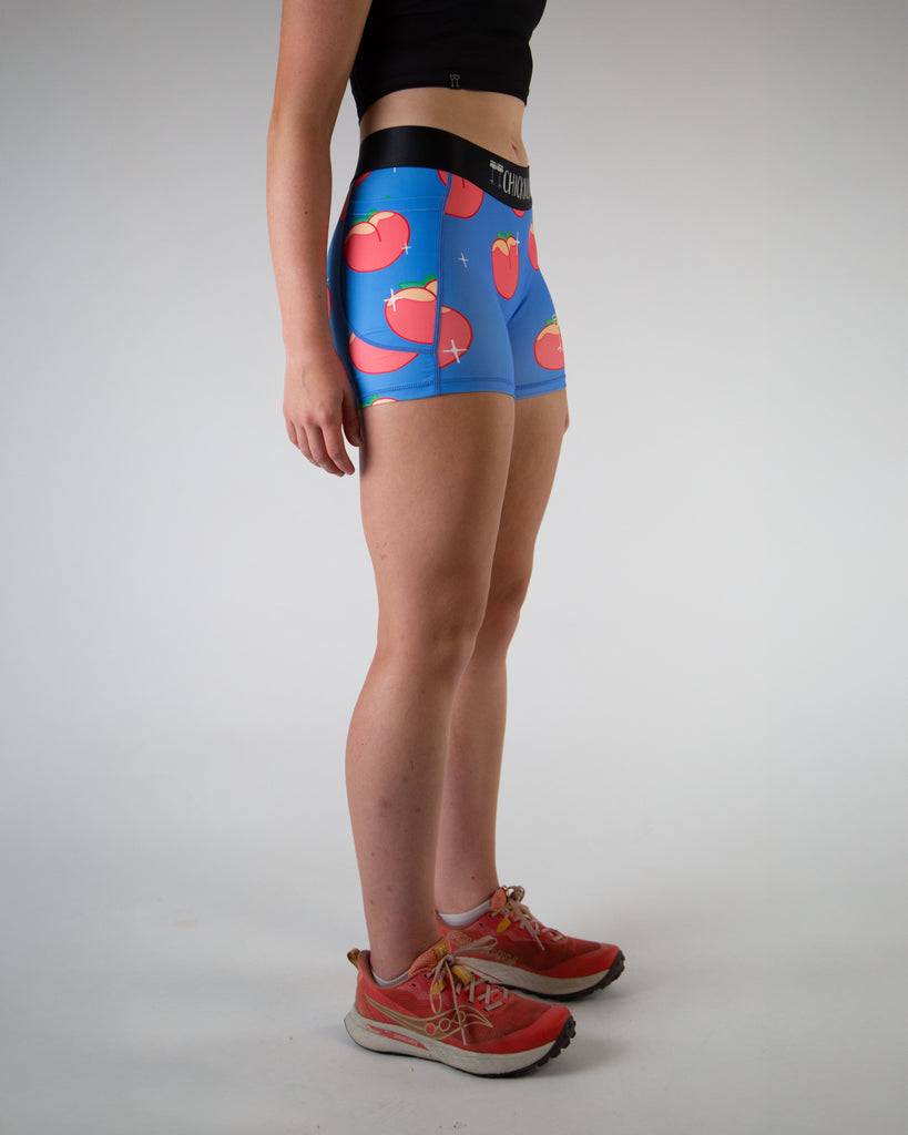Right view of ChicknLegs women’s 3-inch compression spandex shorts, black non chaffing waistband, blue background and juicy peaches on the design.
