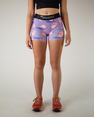 Front view of ChicknLegs women’s 3-inch compression spandex with side pockets, lilac purple background and pink piggies design.