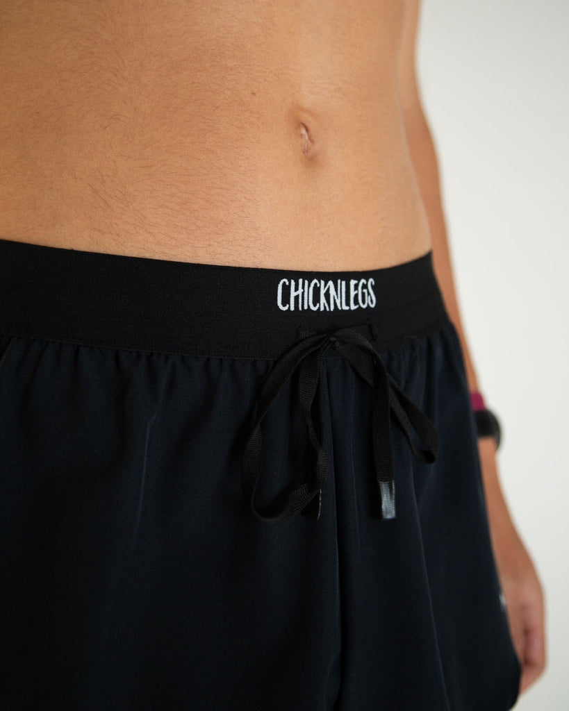 Runner is wearing ChicknLegs in the men's 2 in drawstring in split running shorts. These are the solid color black shorts. A close up image is shown of these to show the drawstrings and waistband!
