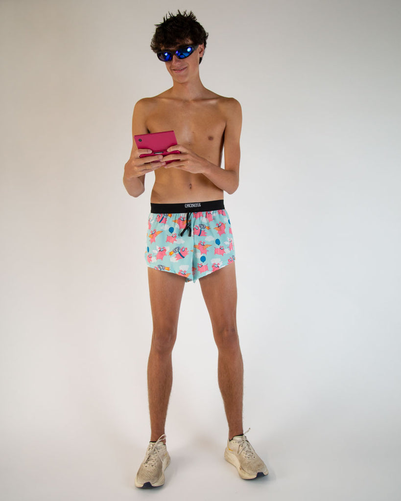 Runner is wearing ChicknLegs in the men's 2 in drawstrings in the split running shorts in the flying pig design. The model is playing with a pink 3DS.