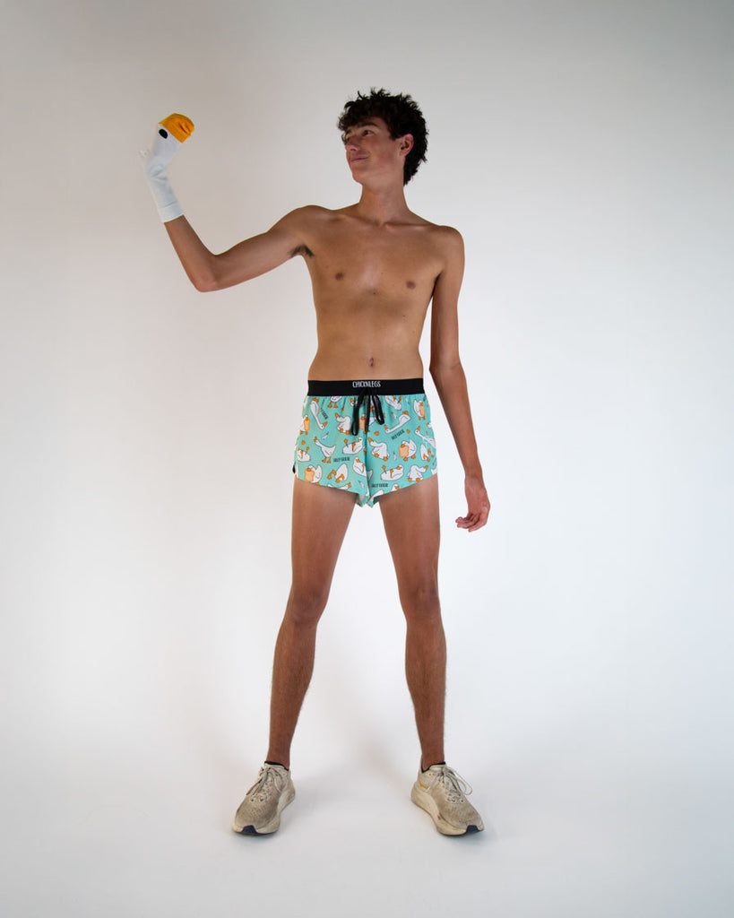Runner is wearing ChicknLegs in the men's 2 in drawstring split running shorts in the Silly Goose design. The model is posing holding a giant goose.
